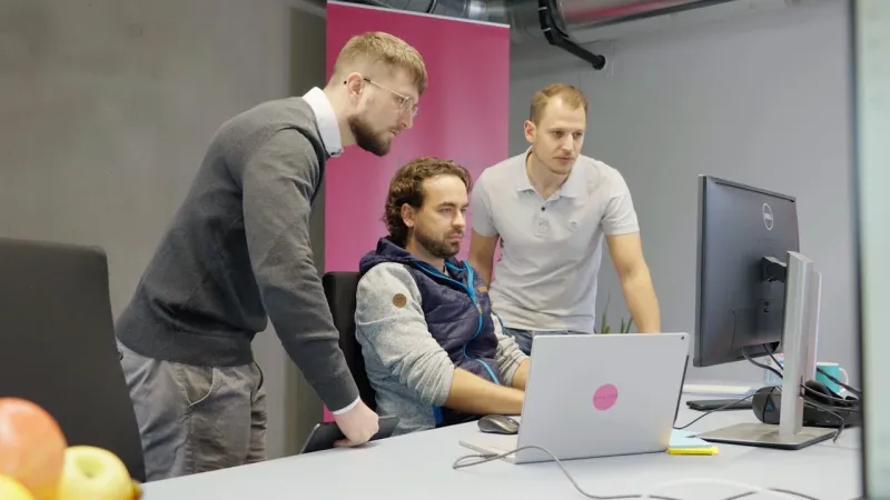 Drei Guid.New Entwickler arbeiten gemeinsam an einem Bildschirm